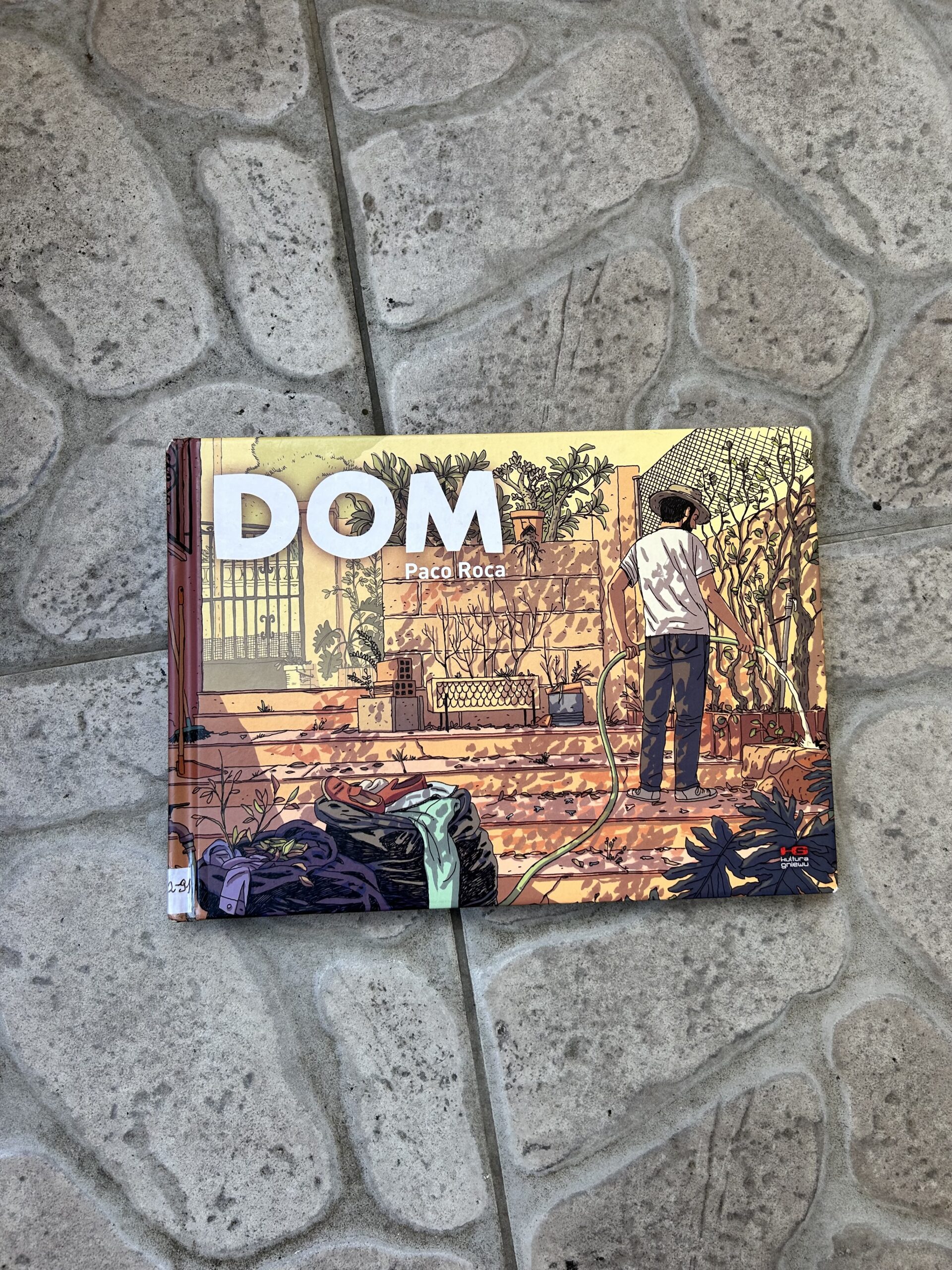 Kolorowe zdjęcie. Książka leży na kamiennej podłodze.