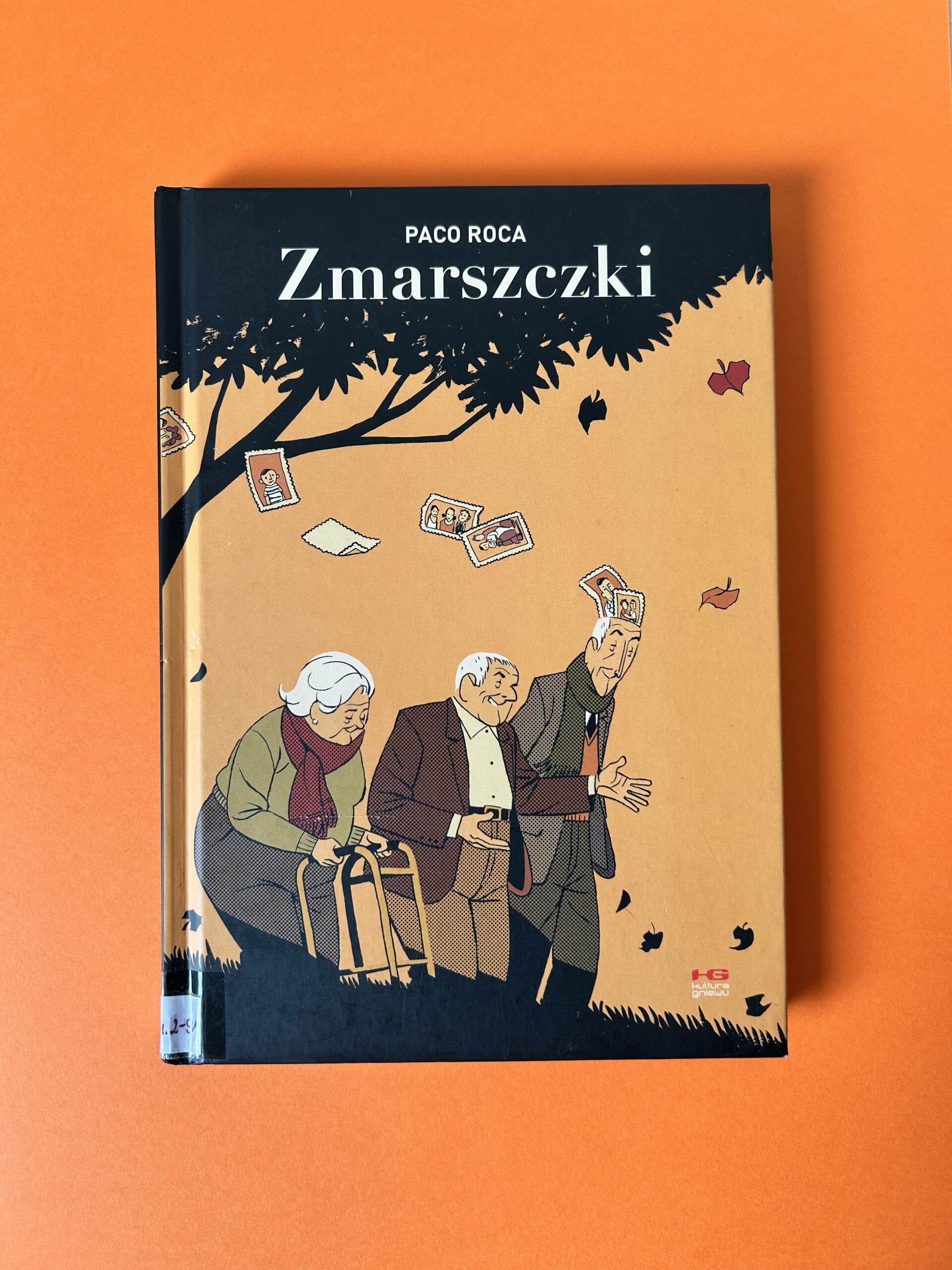Kolorowe zdjęcie. Zamknięta książka leży intensywnie pomarańczowym tle.