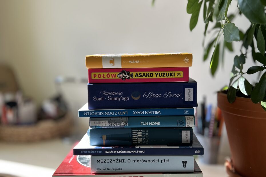 Kolorowe zdjęcie. Stos książek stoi na skraju biurka. Wszystkie są zamknięte. Leżą jedna na drugiej.